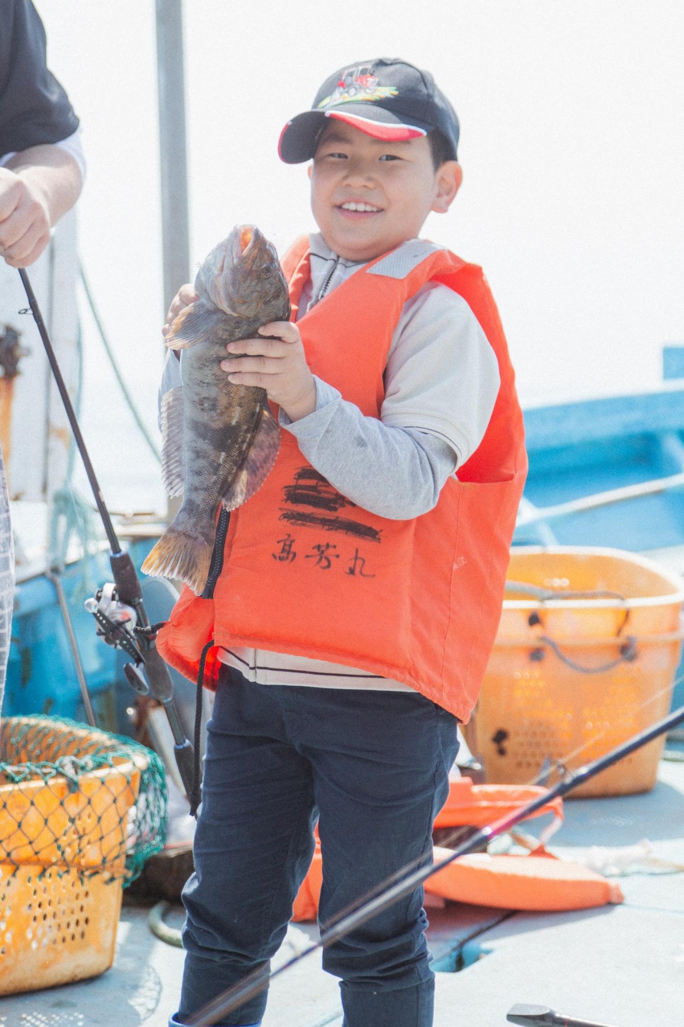 大きなアイナメを両手で持って嬉しそうに笑顔を見せている芳雅くんの写真