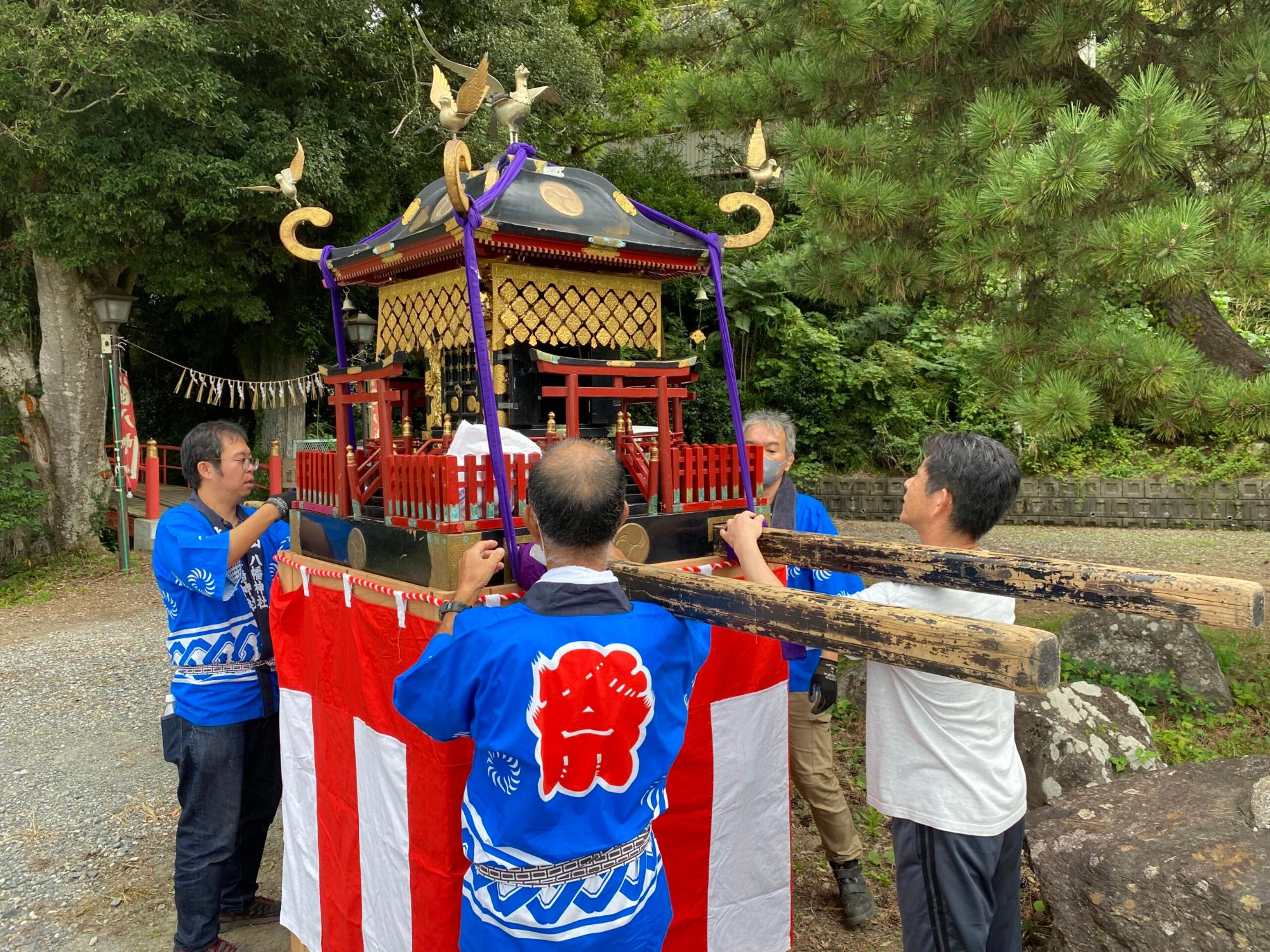 伝統的な神輿を青い法被を着た男性4人が囲み、準備をしている様子の写真