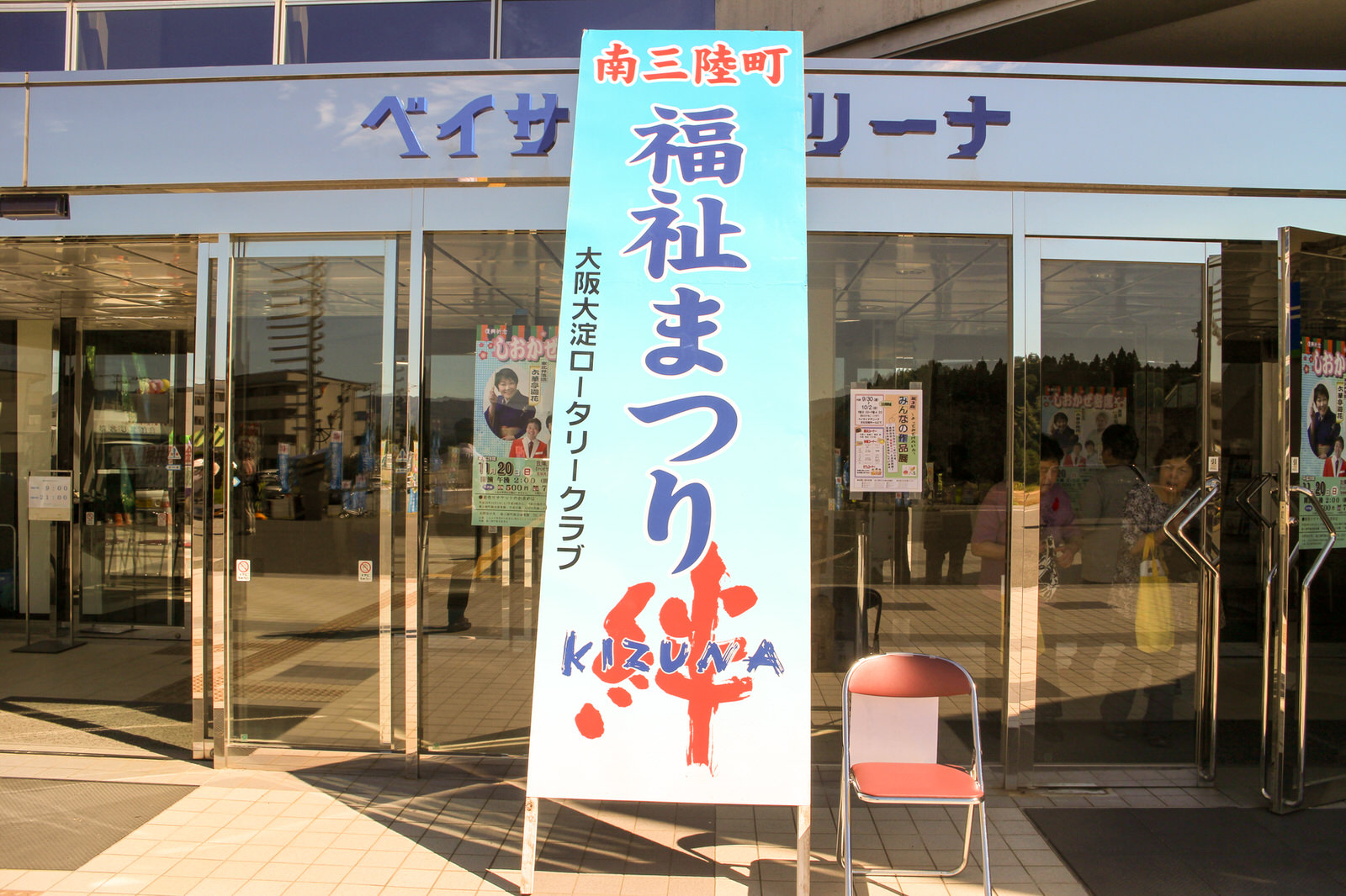 「南三陸町 福祉まつり」と大きく書かれた立て看板が置かれたベイサイドアリーナの入口前の写真