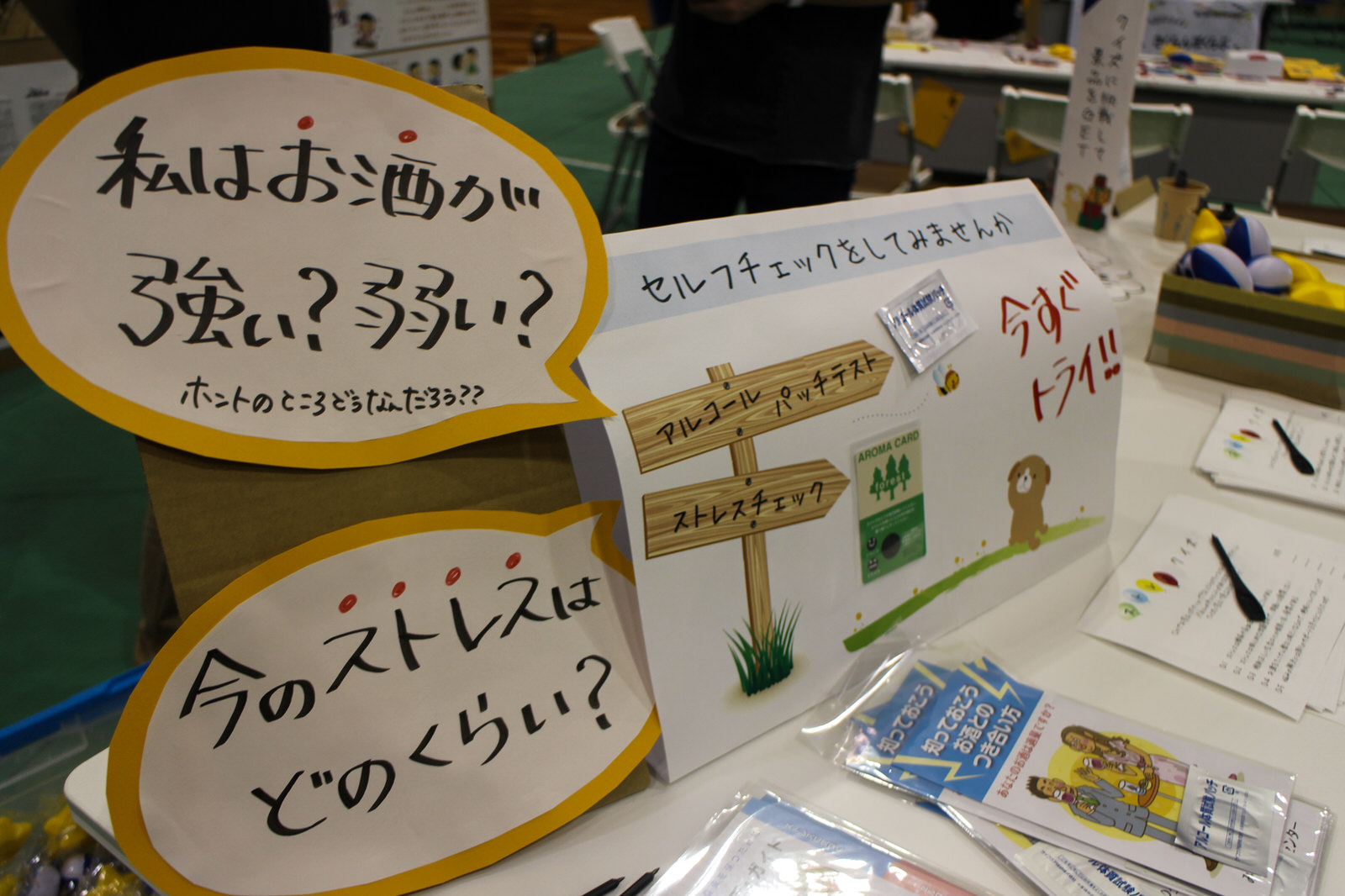 「私はお酒が強い？弱い？」「今のストレスはどのくらい？」などの手書きの吹き出しが書かれたポップと、セルフチェックを促す案内が展示されたブースの写真