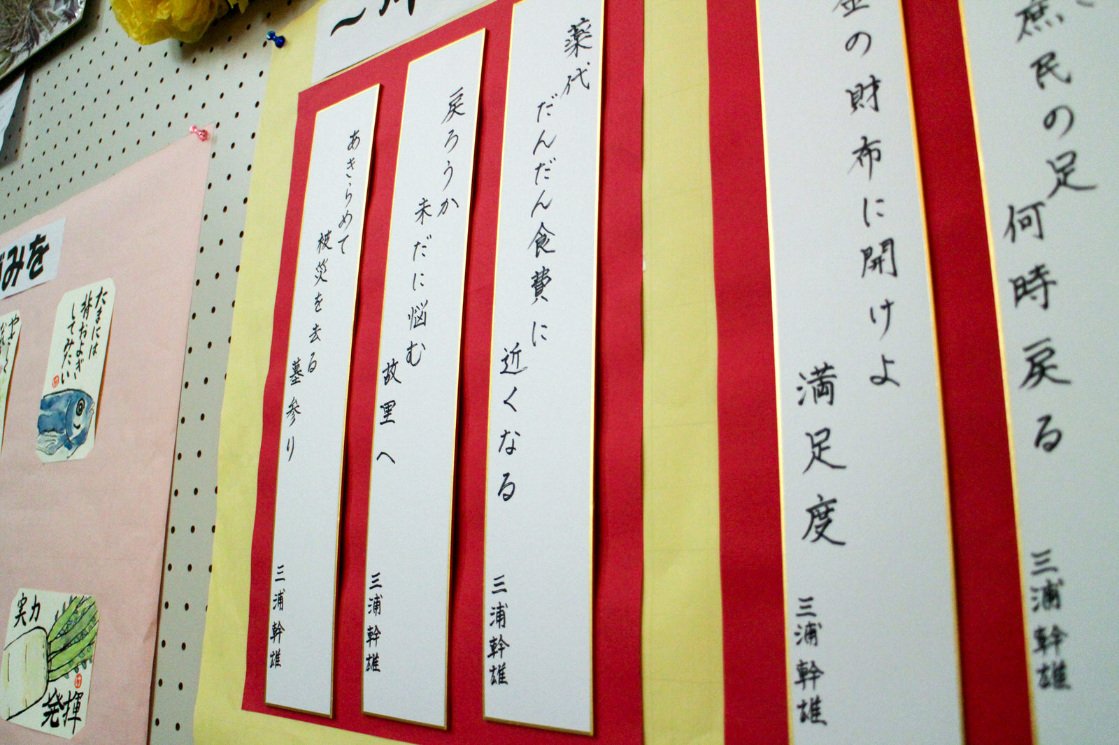 縦長の色紙に書かれた川柳が壁に整然と並んで掲示されている様子を写した展示作品の写真