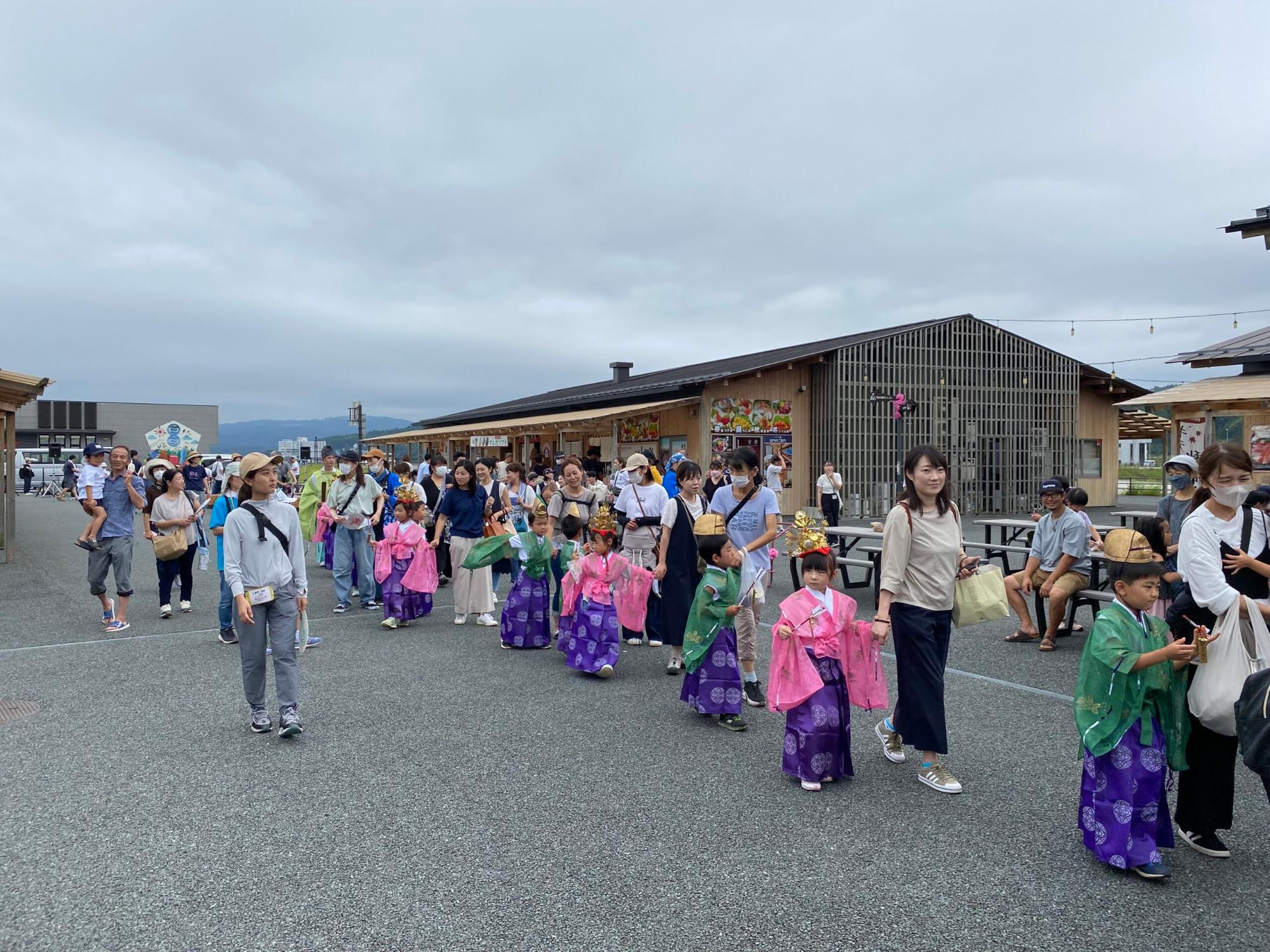 子どもたちが伝統的な和装を身にまとい、大人たちと一緒に屋外を歩いている様子の写真