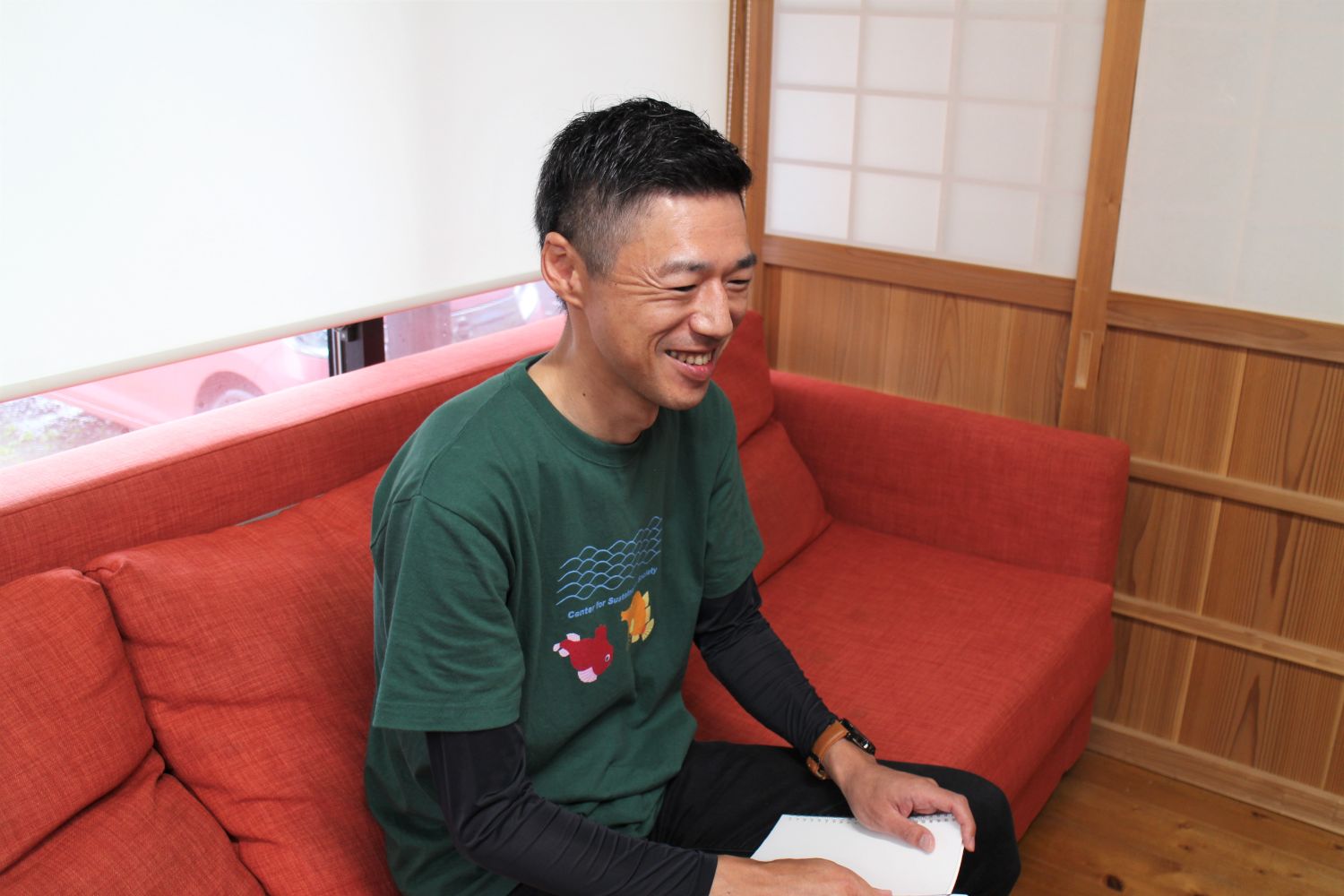 ソファーに座った笑顔の小林さんの横顔の写真