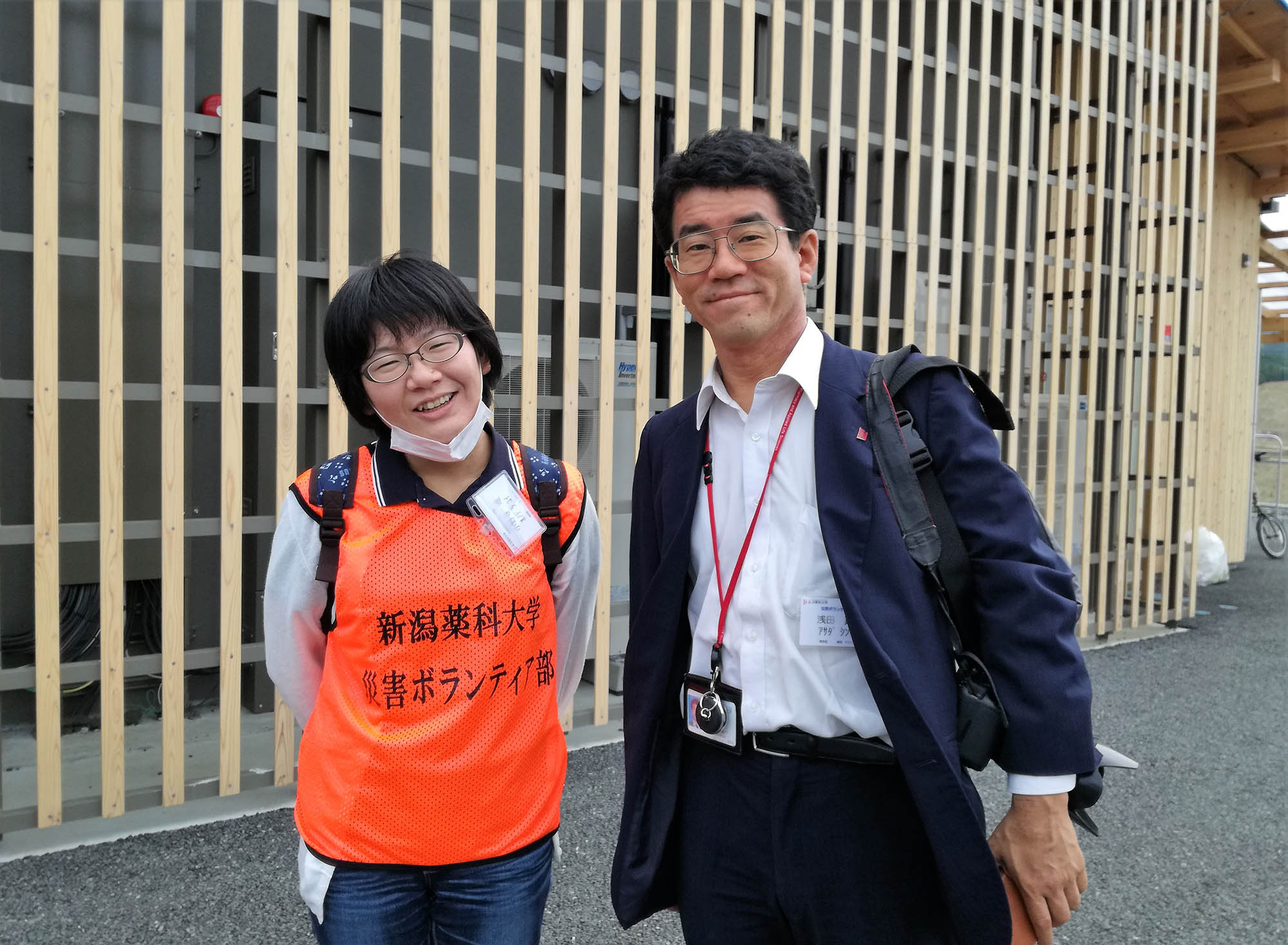 「新潟薬科大学 災害ボランティア部」のビブスを着た小野寺唯さんとスーツ姿の浅田真一先生が笑顔で並んで写っている写真