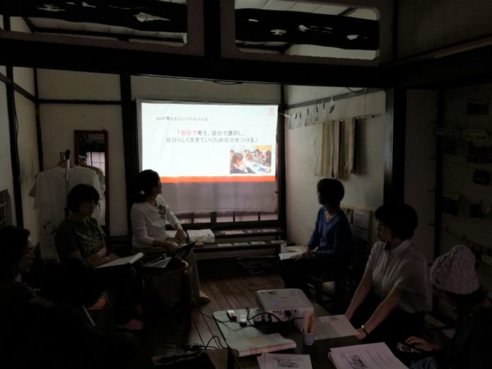 中央にプロジェクターに映像が映し出されており、和室のような落ち着いた空間で行われている活動の様子の写真