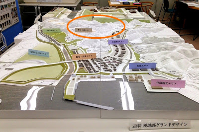 被災地全体の地形模型に色と文字で用途エリアが表示され、造成地のエリアがオレンジの円で囲まれている模型の写真