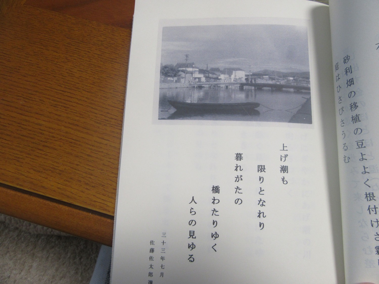 上部にはモノクロの港町の写真が載っており、下には縦書きの短歌が記されている句集の1ページをアップで撮影した写真