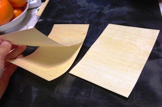 非常に薄く加工された木の板を手にしてめくっている様子を写した写真