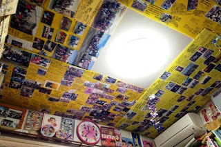 壁や天井にびっしりと埋められた写真や黄色い紙が貼られた天井を写した写真