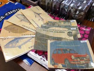 薄い木板に魚のイラストと名前、昭和レトロな日本車が印刷され展示されている写真