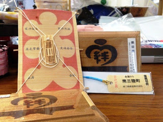 2種類の木製プレート、木製タグに「南三陸町」の文字に青い紐がついたトラップ並べられた写真