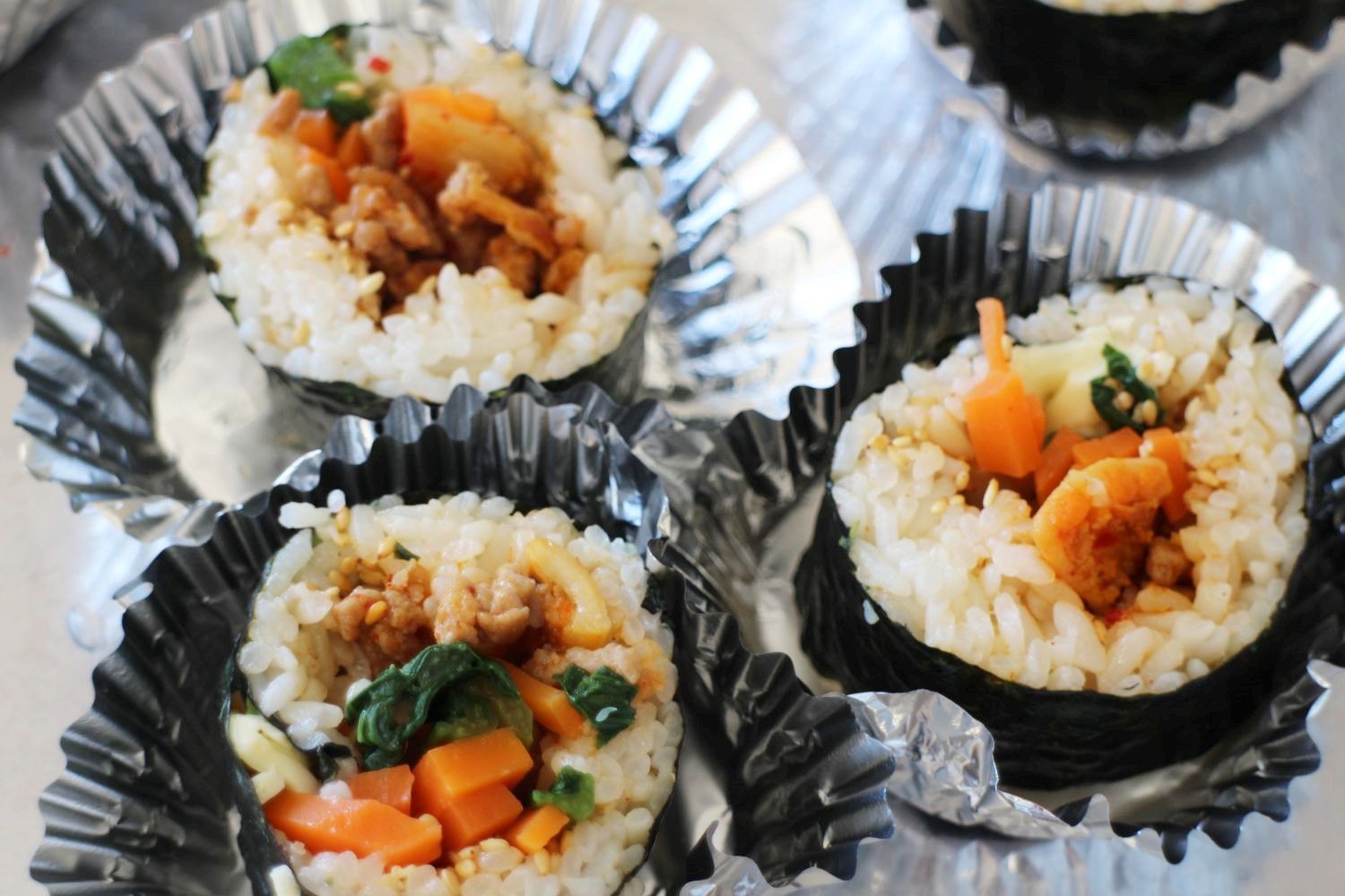 アルミホイルのカップに、ニンジン・ほうれん草・ホヤなどの具材が入ったホヤチーズキンパの写真