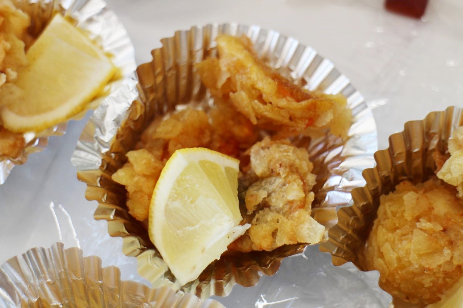 アルミカップに入った唐揚げにレモンが添えられている写真