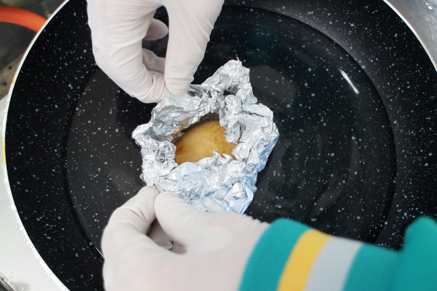 アルミホイルで包んだホヤを水を張ったフライパンに入れている手元の写真