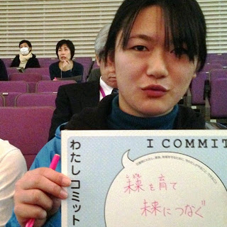 女性が「未来を育て未来につなぐ」という文字が書かれた紙を持っている写真