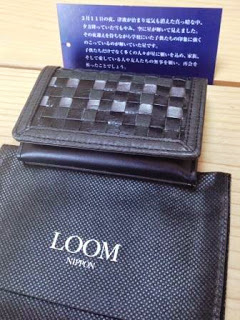 黒のチェック柄の名刺入れの様な物と「LOOM NIPPON」と書かれた黒い袋が机の上に置かれている写真