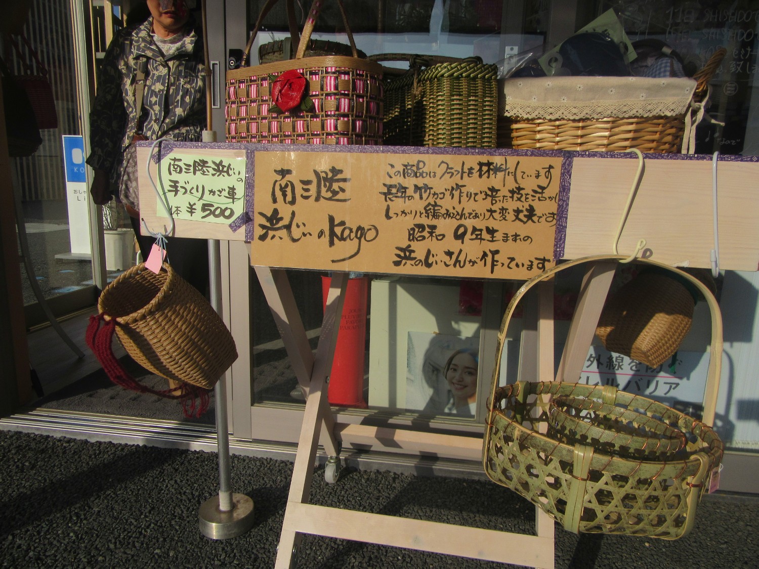 店先に置かれた「南三陸 浜じぃのKago」と書かれた手書きの案内板が掲げられている台に、複数の手作りの竹かごが並べられている写真