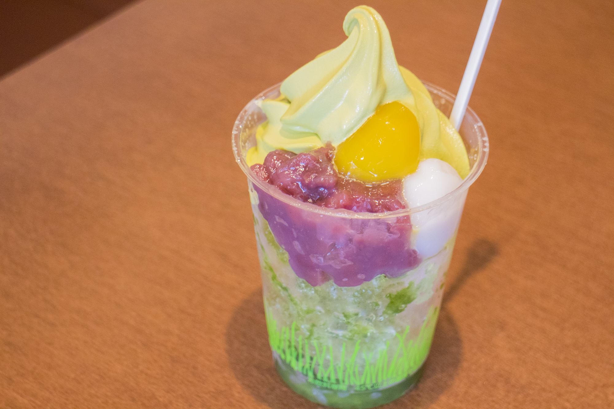 透明のカップに小豆や白玉、緑色のソフトクリームが入ったスイーツの写真