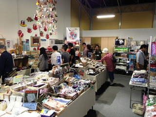 食品や雑貨が並ぶ棚が壁際や中央にたくさん置かれた店内たくさんの人が見て回っている様子の写真