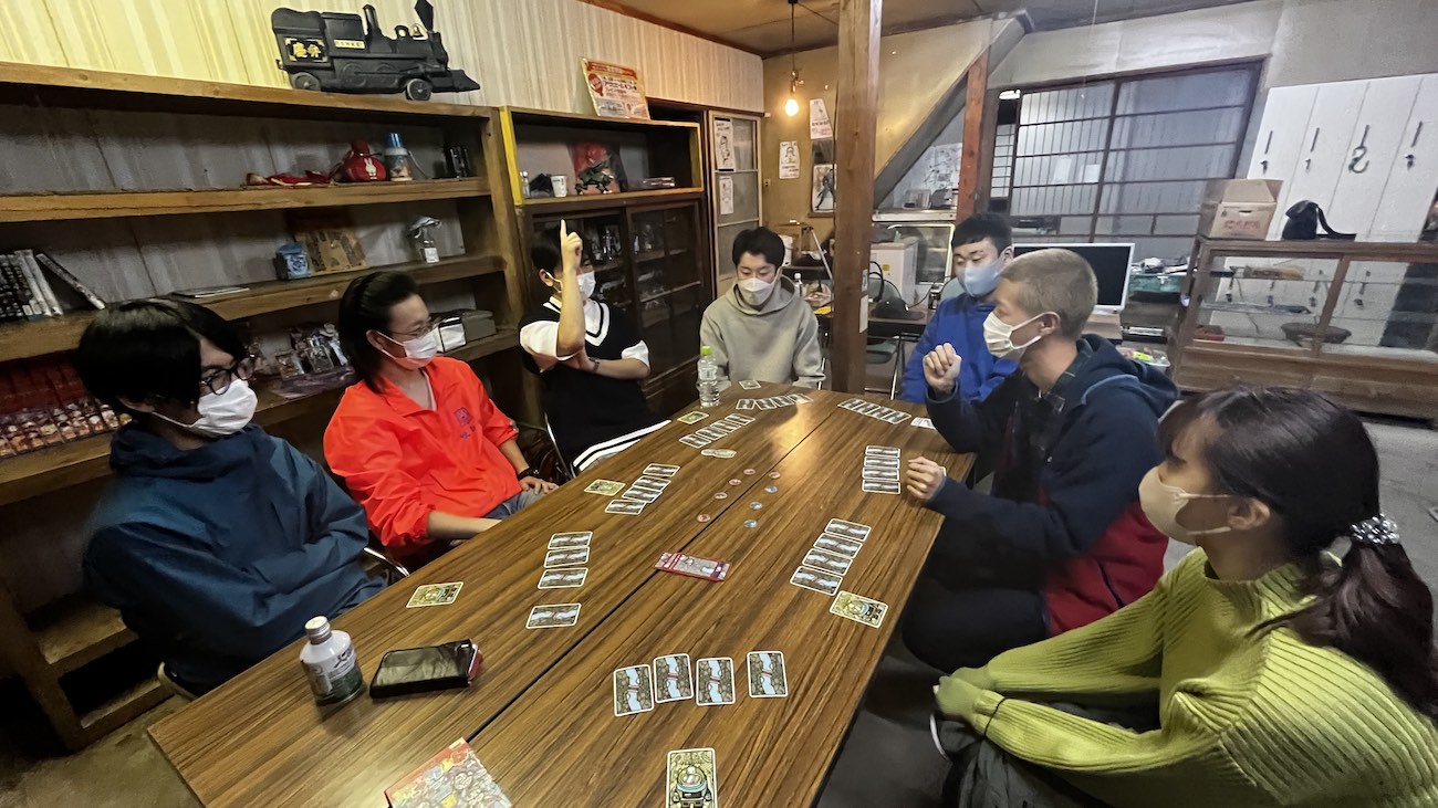 和室でテーブルを囲み、カードゲームを楽しみながら交流している様子の写真