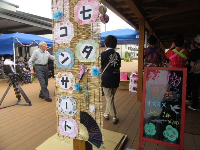 軒下にかけられた、「七夕コンサート」の文字がと飾りが貼りつけられたすだれの横に、「えんがわカフェ」と書かれた黒板が立っており、横には青いテントが準備されている写真