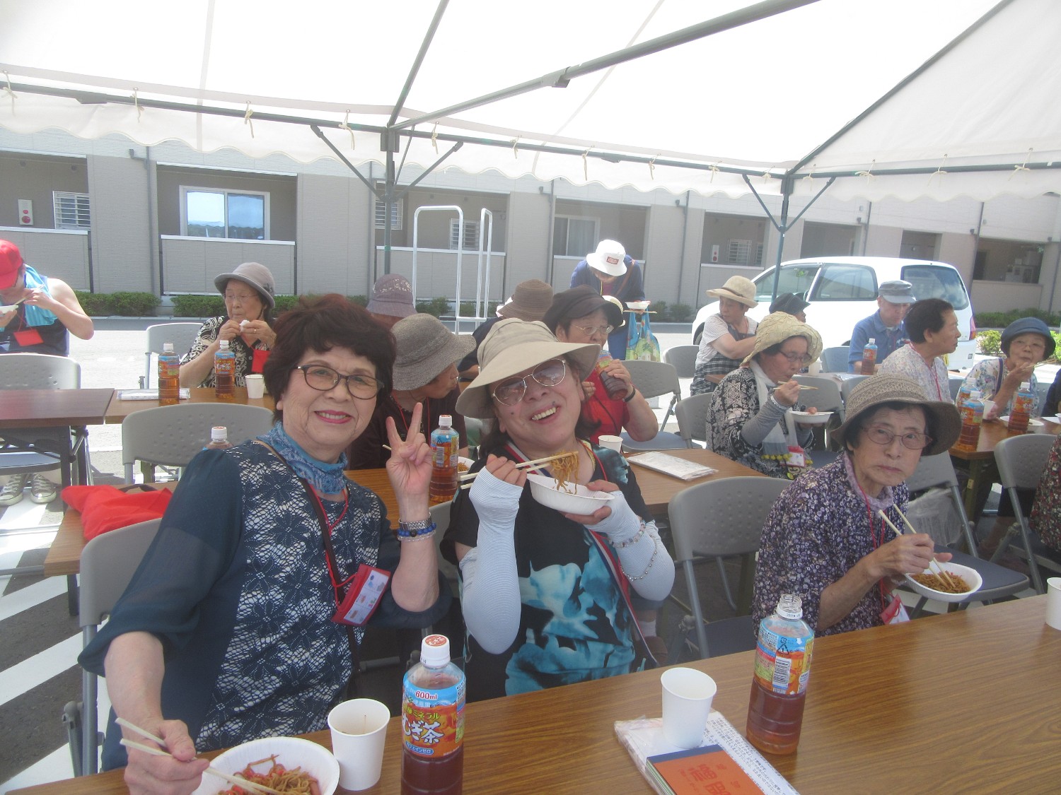 白いテントの下で食事を楽しむ女性2人を写した写真