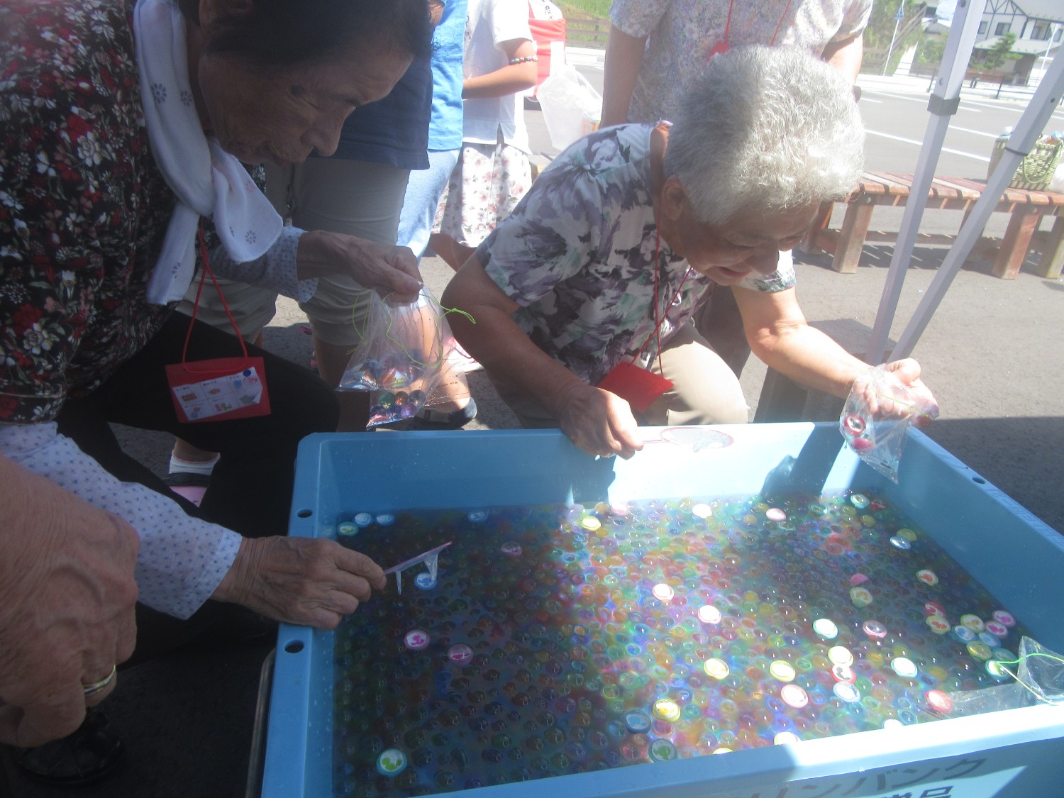小さなプールの中には、赤、青、黄色、緑などカラフルなゴムのボールがたくさん浮かんでおり女性2人がボールすくいを楽しむ様子の写真