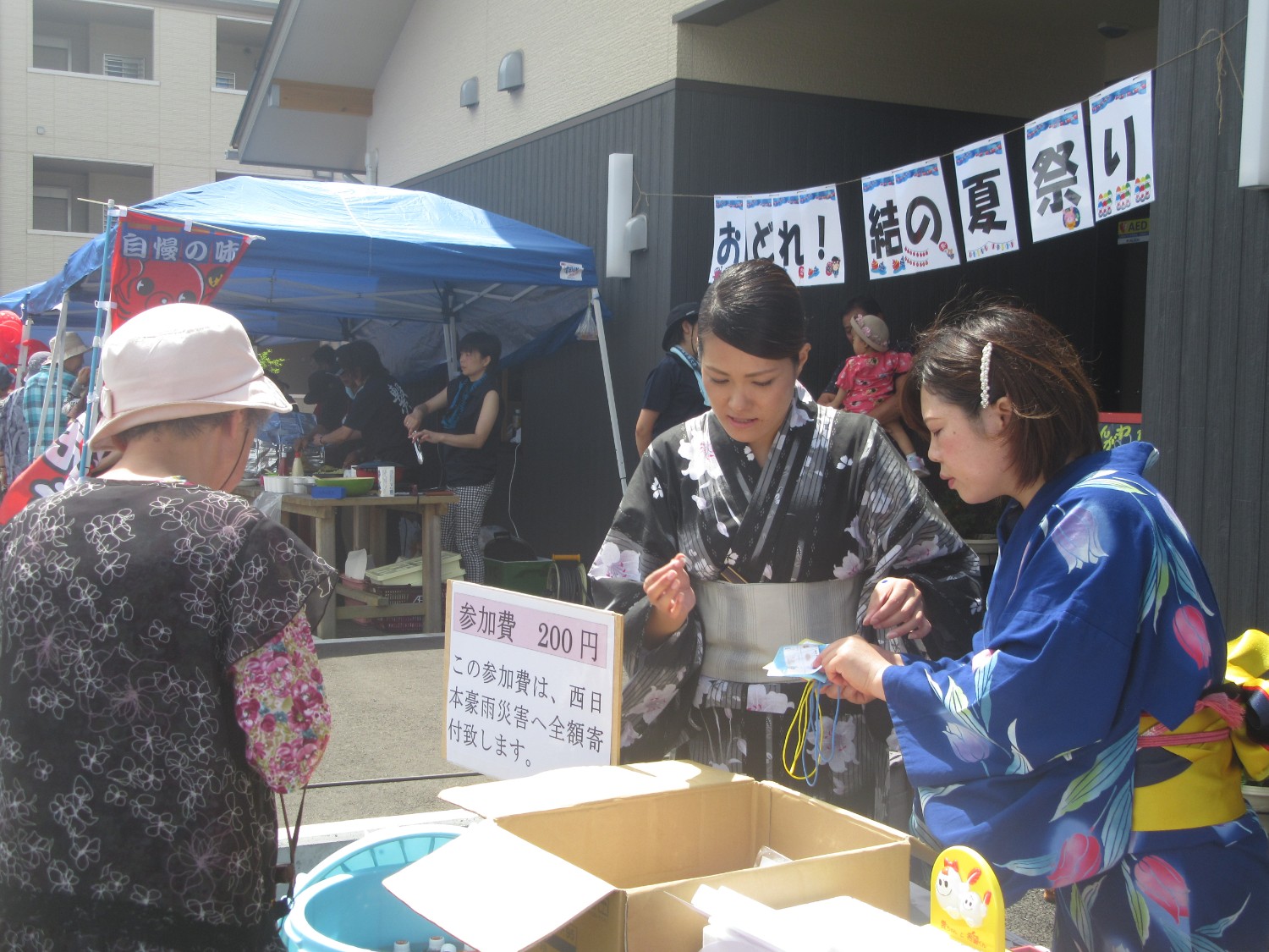 黒と紺の浴衣を着た関係者の女性2人が参加者から参加費を集めている様子の写真