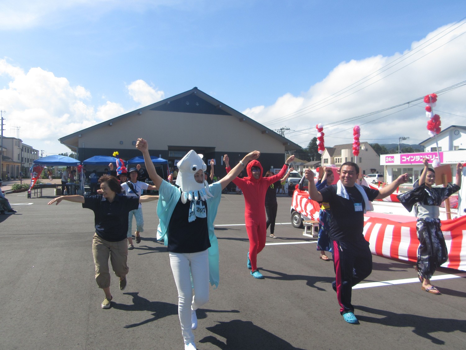 魚の着ぐるみを着た人、町の名物をモチーフにした仮装した人たちが楽しそうに踊っている写真