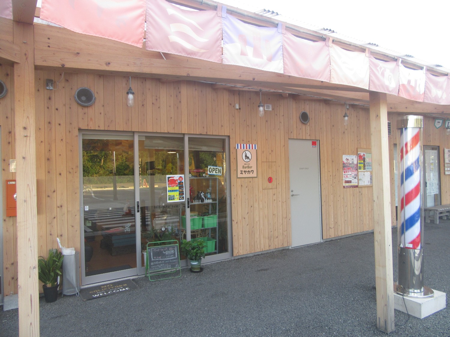 木造の建物の外にある理容室の入口と赤白青の回転灯が写っている写真