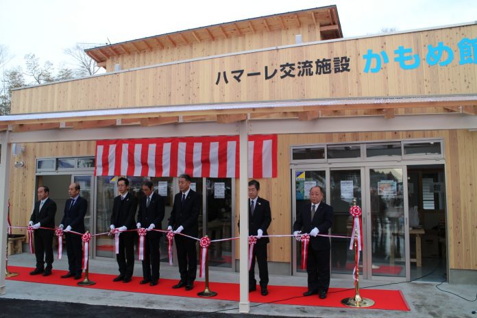 新しく完成したハマーレ歌津の交流施設「かもめ館」の前で、複数のスーツ姿の男性が白手袋をしてテープカットのセレモニーを行っている様子の写真