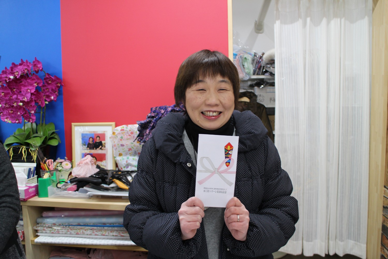 牧野美紀さんが祝儀袋を両手で持って笑顔で写っている写真