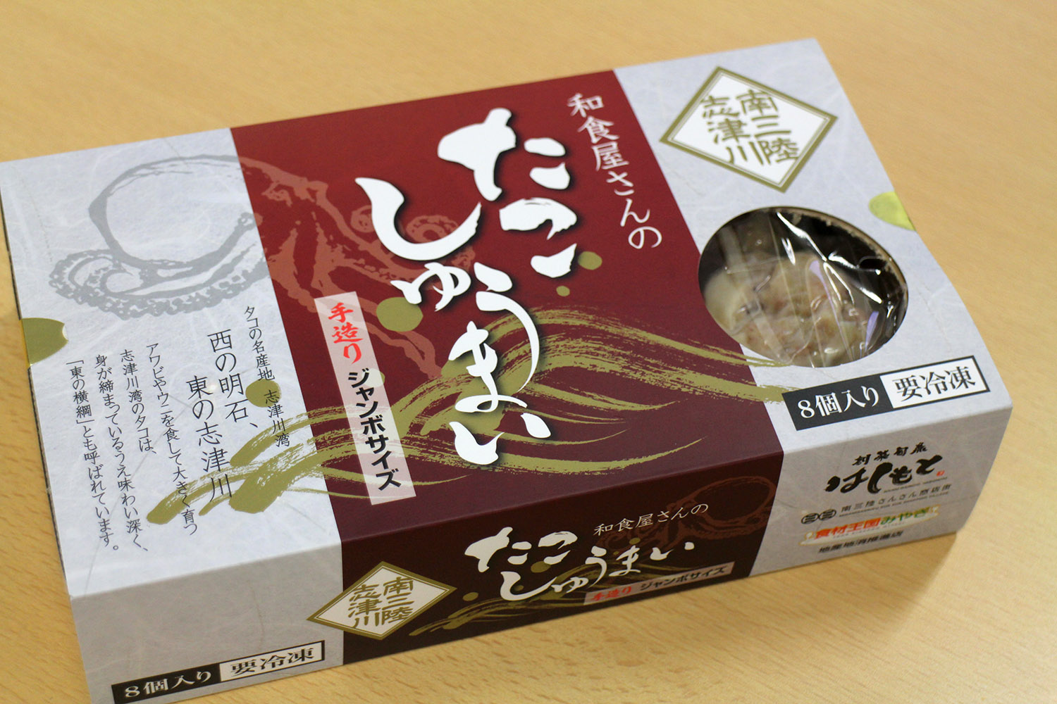 中身のしゅうまいが一部見えるようになっている 「たこしゅうまい」と書かれたえんじ色とグレーの配色の箱入りの商品の写真