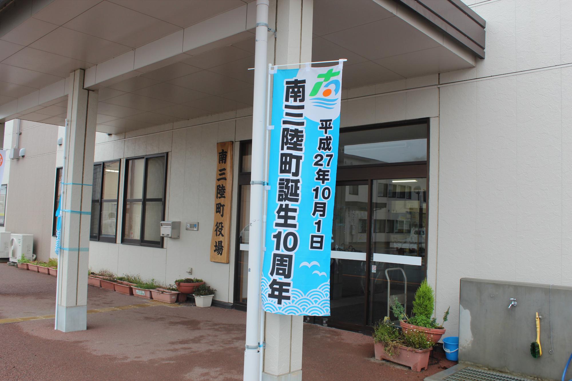 玄関横の柱に水色の南三陸町誕生10周年のぼり旗が設置されている様子を写した写真