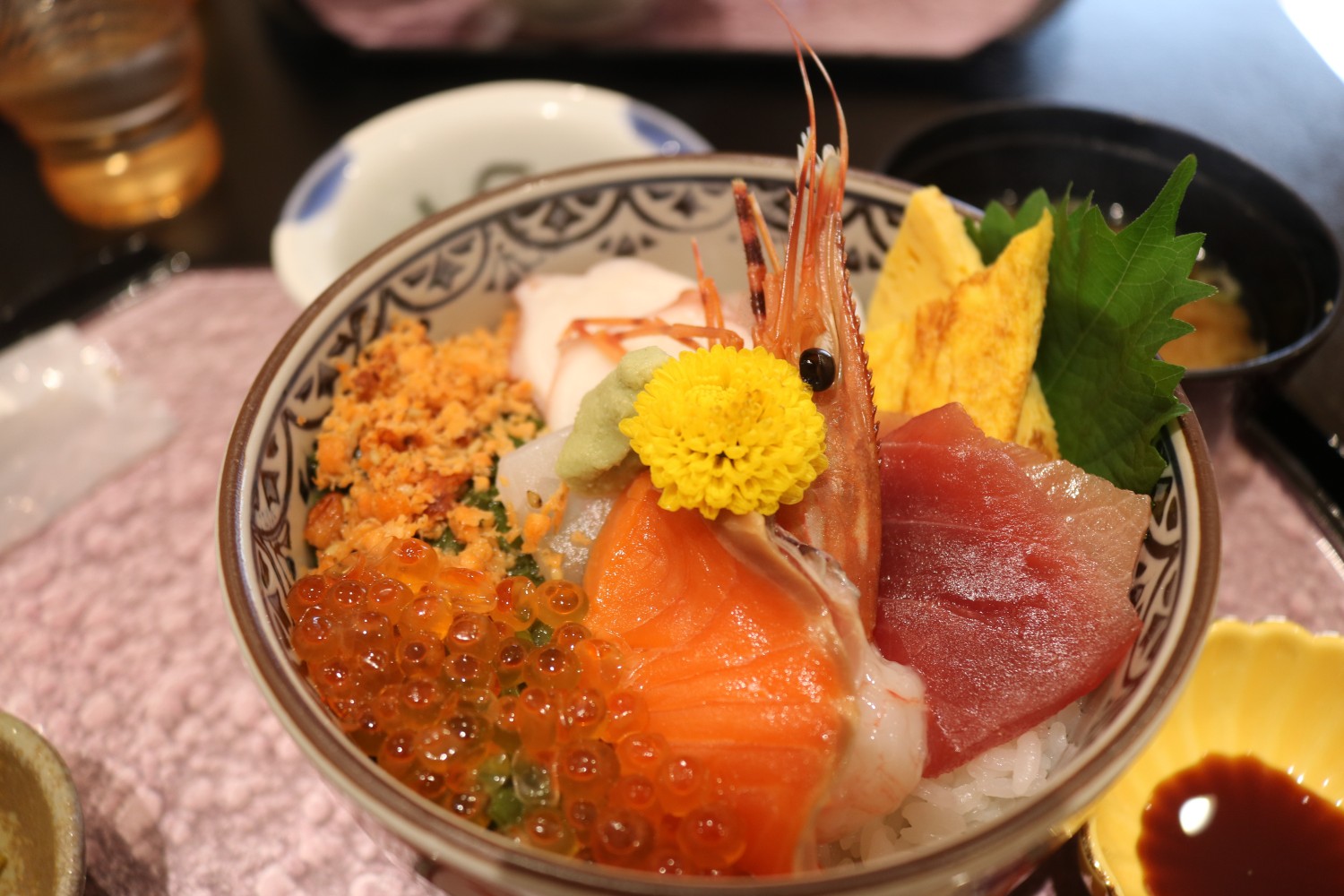 サーモン、マグロ、イクラ、エビ、卵焼きなどが彩りよく盛り付けられた海鮮丼の料理をアップで撮影した写真