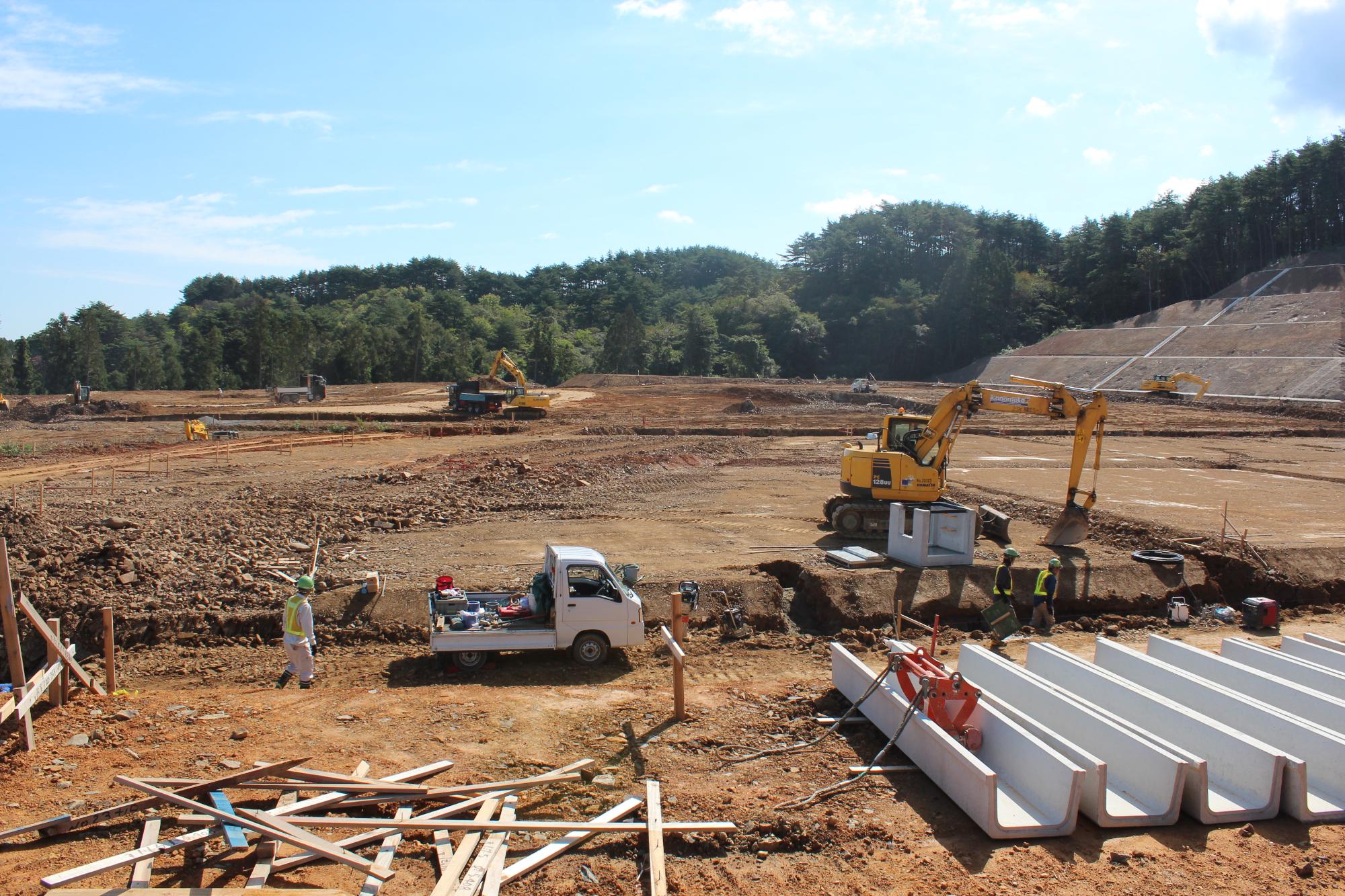 複数の重機や作業員が土木工事を進めている広大な建設現場の写真