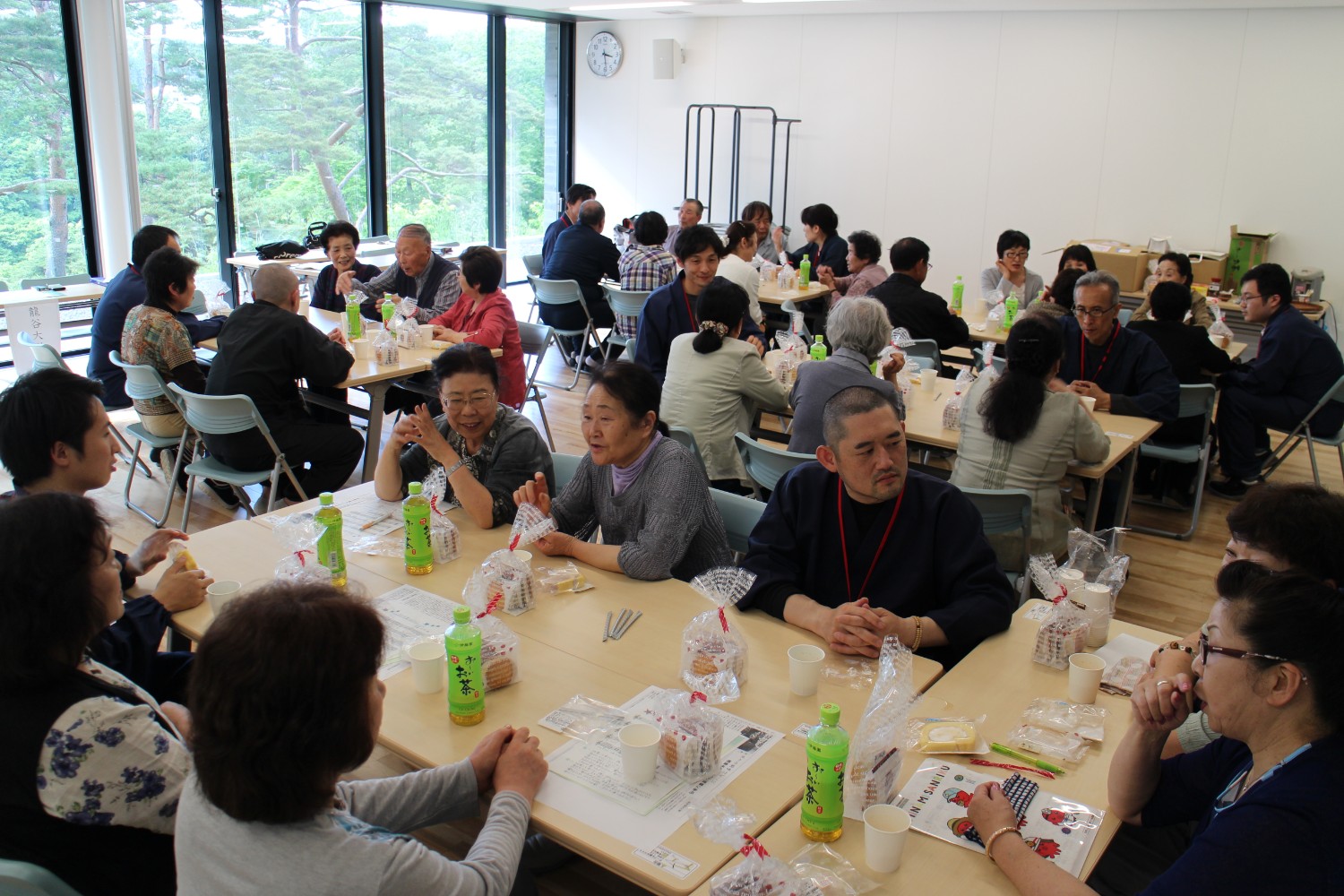 参加者と支援者がテーブルを囲みお茶やお菓子を食べながら和やかに談笑している交流会の写真