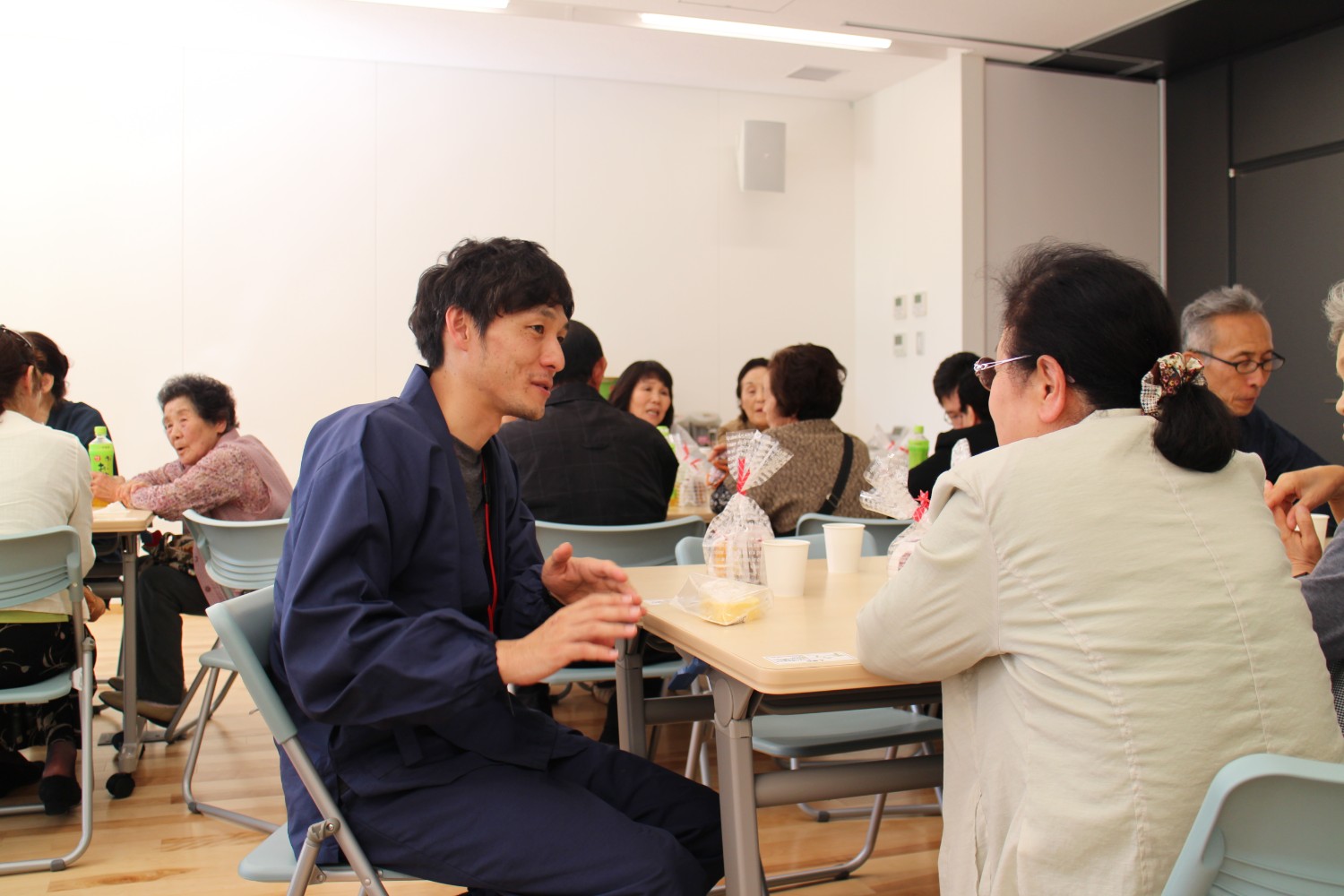 男性支援者が高齢の女性参加者と向き合って真剣に会話している復興支援交流会の様子の写真