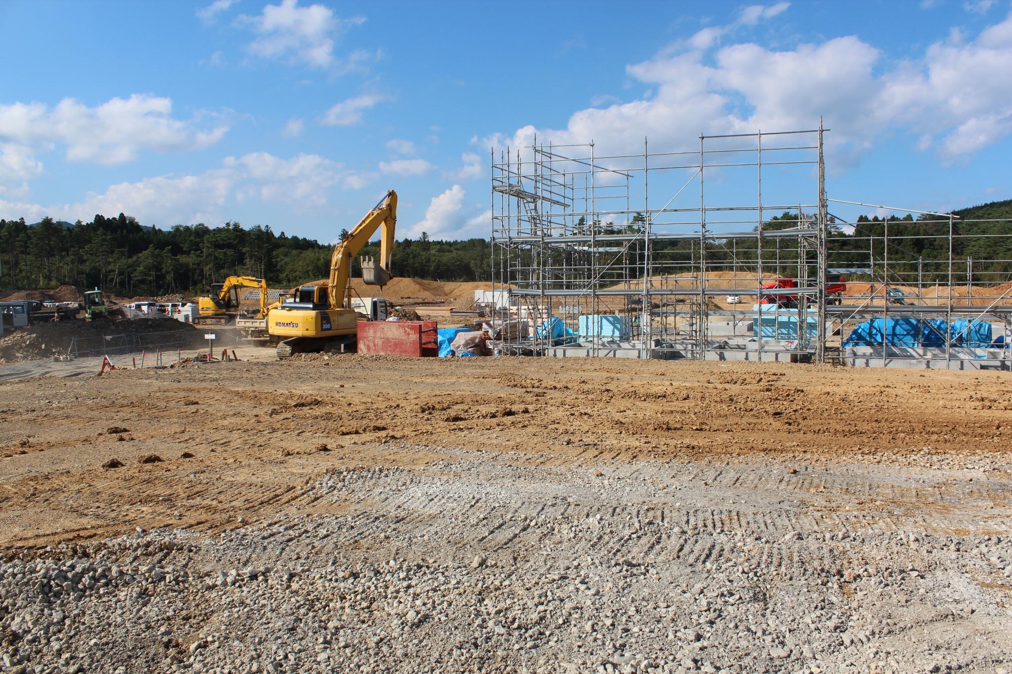 足場が組まれ建物の基礎と重機が並ぶ建設現場の発展途中の写真