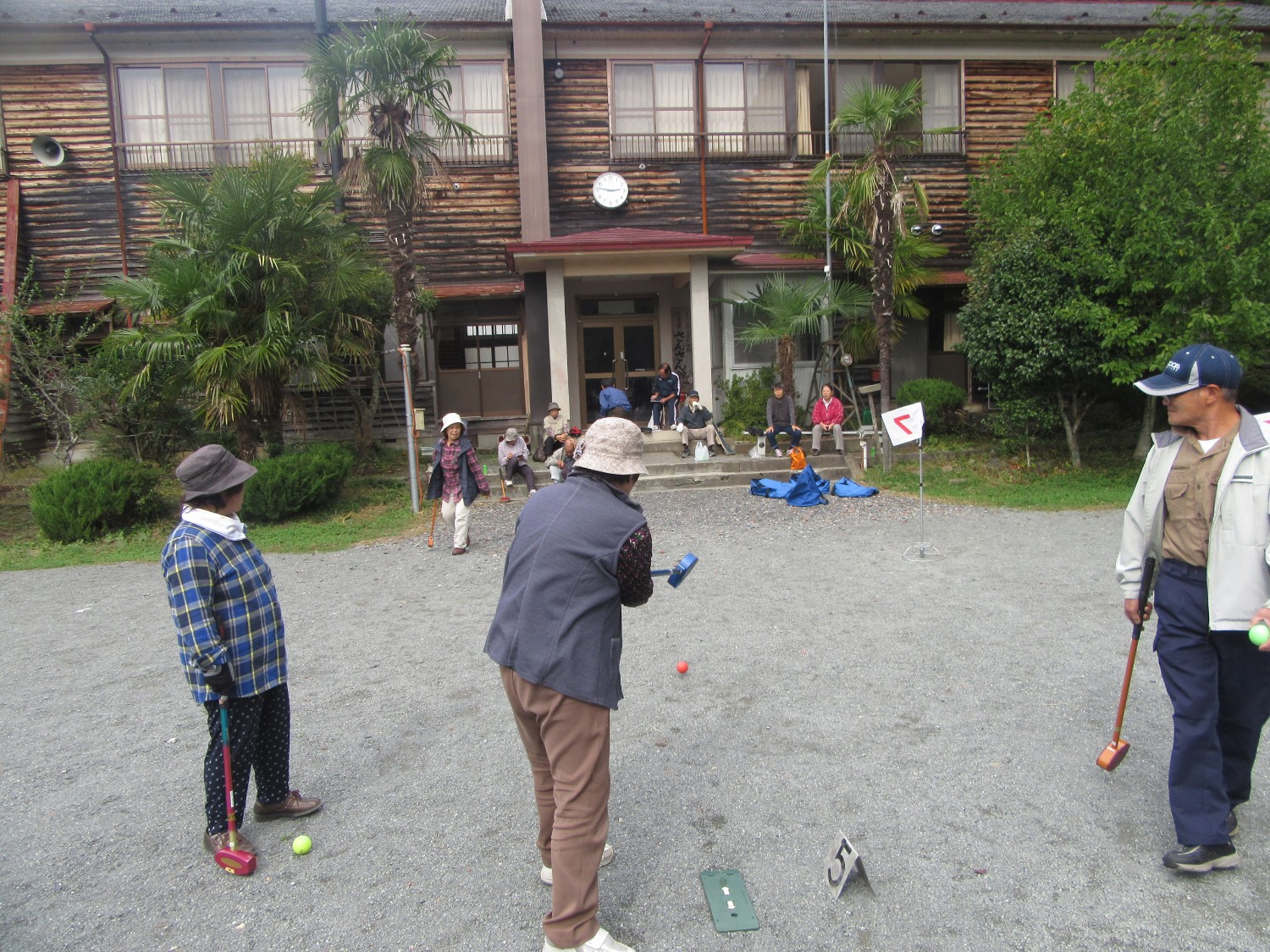 屋外で数人の高齢者がゲートボールを楽しんでいる様子の写真