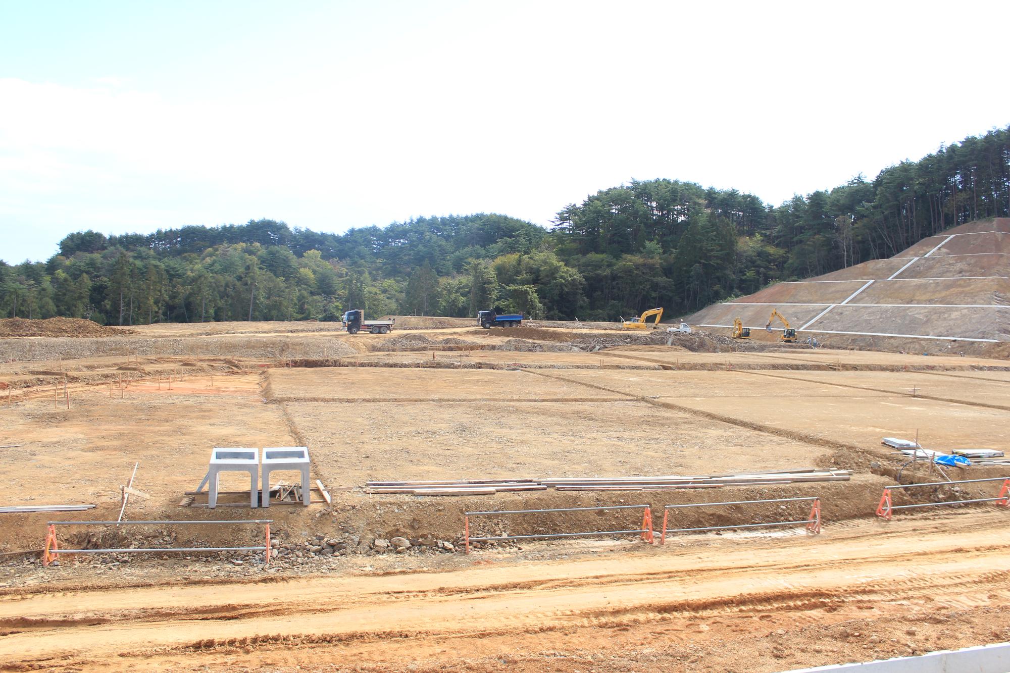整地が進み重機やトラックが作業している広大な造成地の写真