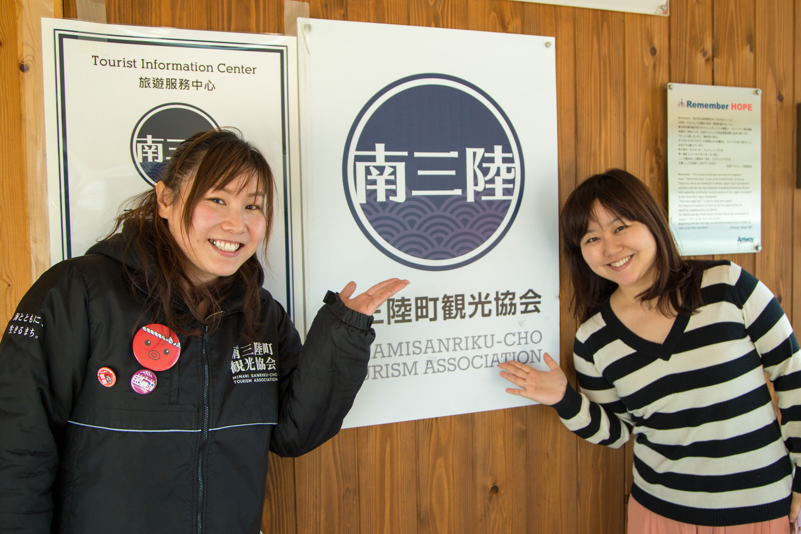 壁に貼られた南三陸町観光協会のポスターを左右に立った千葉さんと女性リポーターが手で指している写真