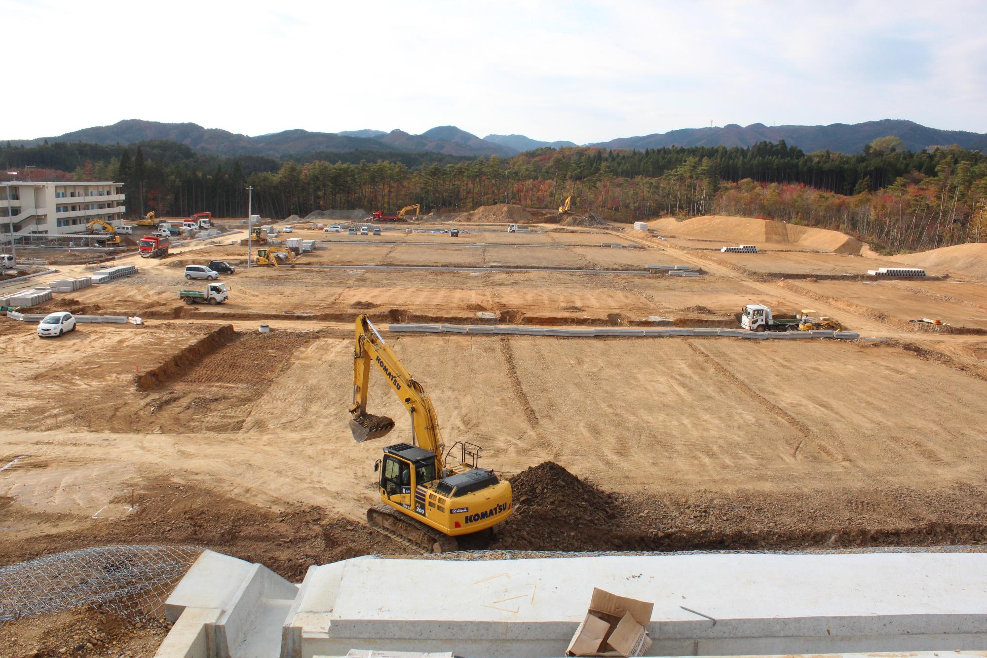 広大な土地が整地され、複数の重機や車両が稼働している様子を高所から撮影した造成中の写真