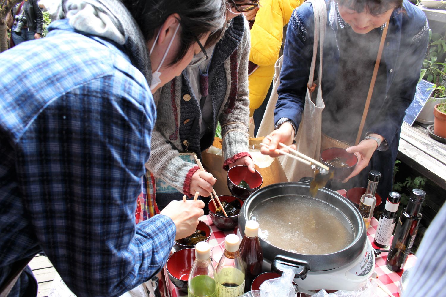 3人の来場者たちが湯気の立つ大きな鍋で、生わかめをしゃぶしゃぶしている様子が写された写真