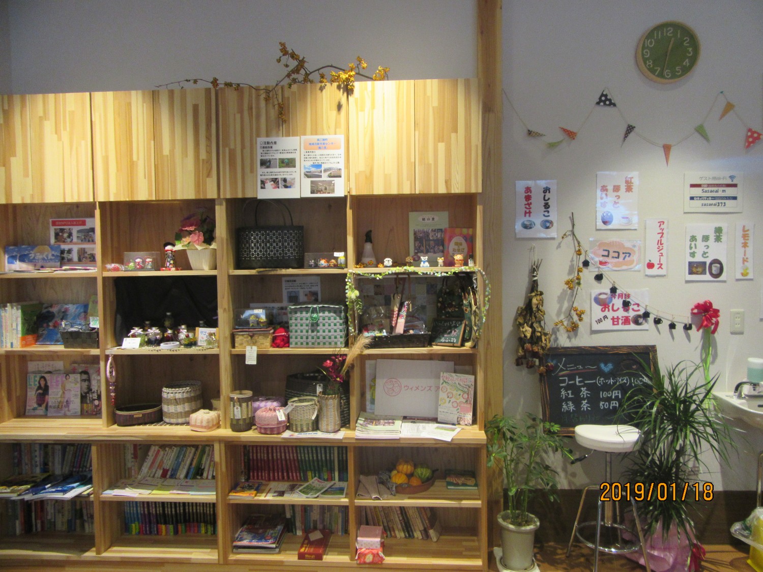 棚に本や小物が整然と並べられ、壁にはポスターやメニューが貼られている『えんがわカフェ』手作り作品の展示販売コーナーの写真