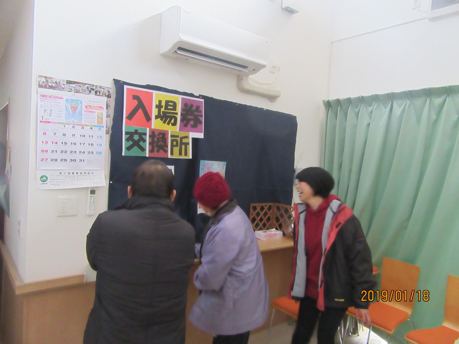 入場券交換所の前に3人の人が順番を待つように並んで立っている写真