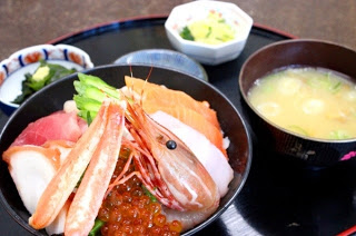 丼にマグロ、エビ、イクラ、サーモンなどの海鮮が彩りよく盛られ、味噌汁と小鉢、漬物が添えられた海鮮丼の料理をアップで撮影した写真