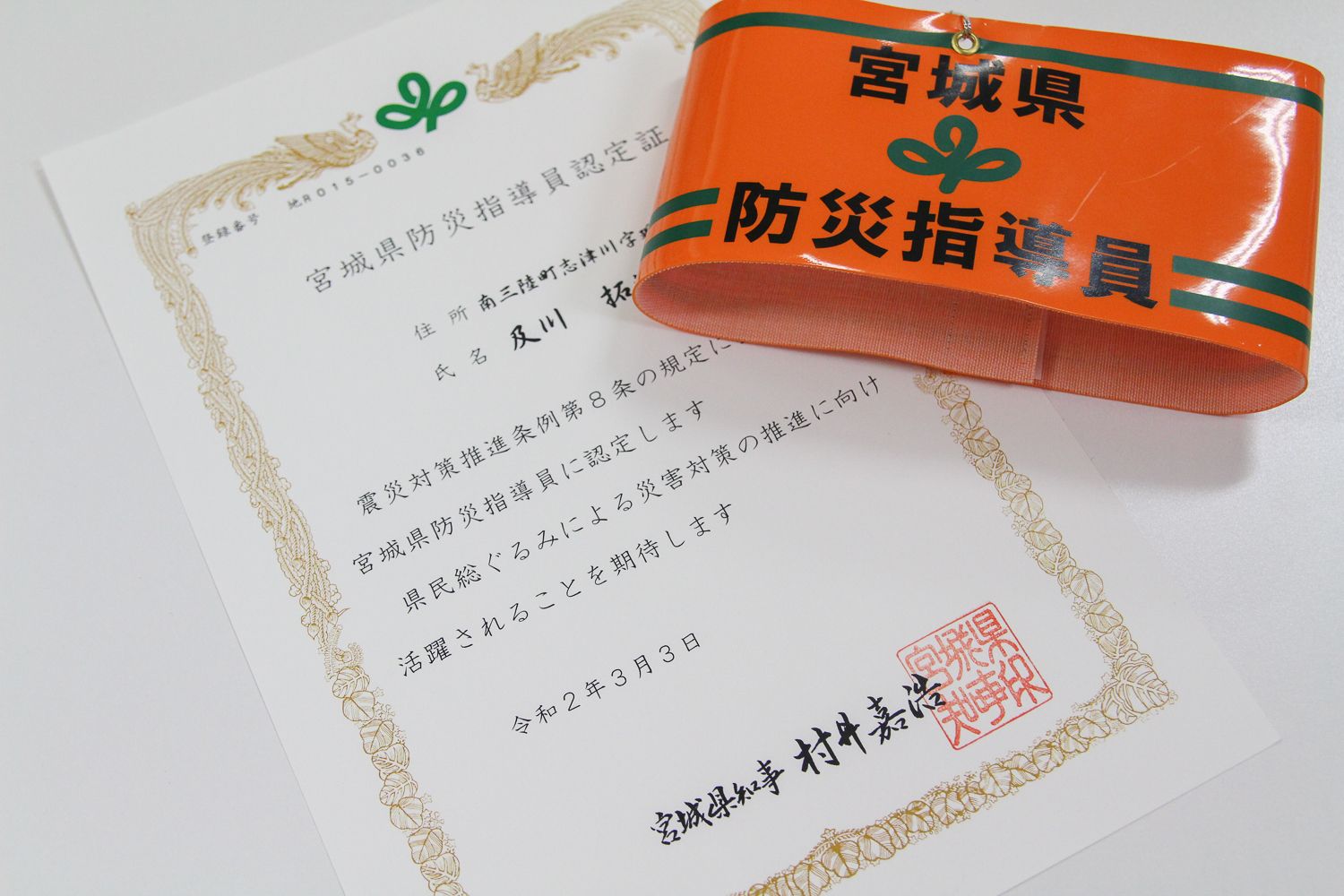 宮城県防災指導員認定証とオレンジ色の腕章が並べて置かれている写真
