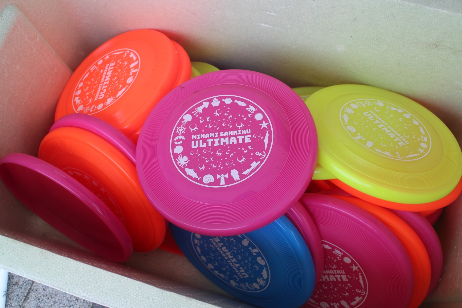 沢山のピンク、黄色、オレンジ、青のオリジナルのミニディスクが箱に入った写真