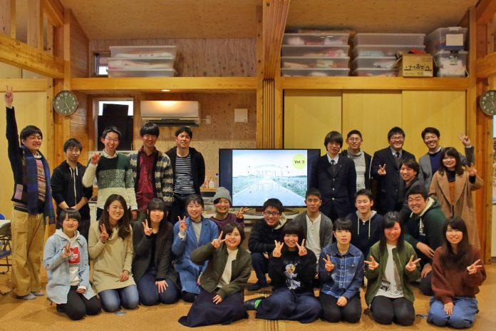 木造の温かみのある室内で、「みらいカフェ Vol.3」と表示されている中央のモニターを挟んで25名の若者たちが前列・中列・後列に分かれて記念撮影をしている写真